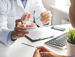 Dentist showing patient model of teeth