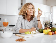 Woman smiling while eating fruit in kitchen