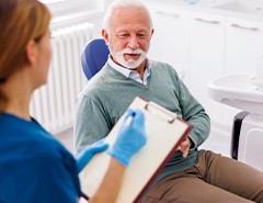 Dentist taking notes on clipboard while talking to patient