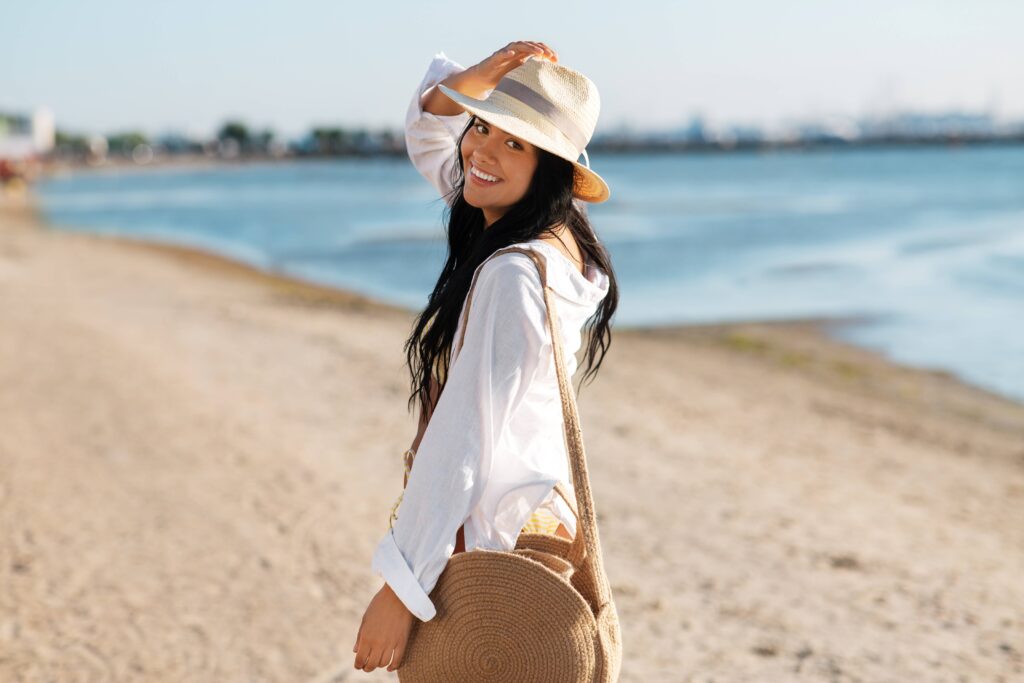 Woman in sunhat walking on beach in the summer