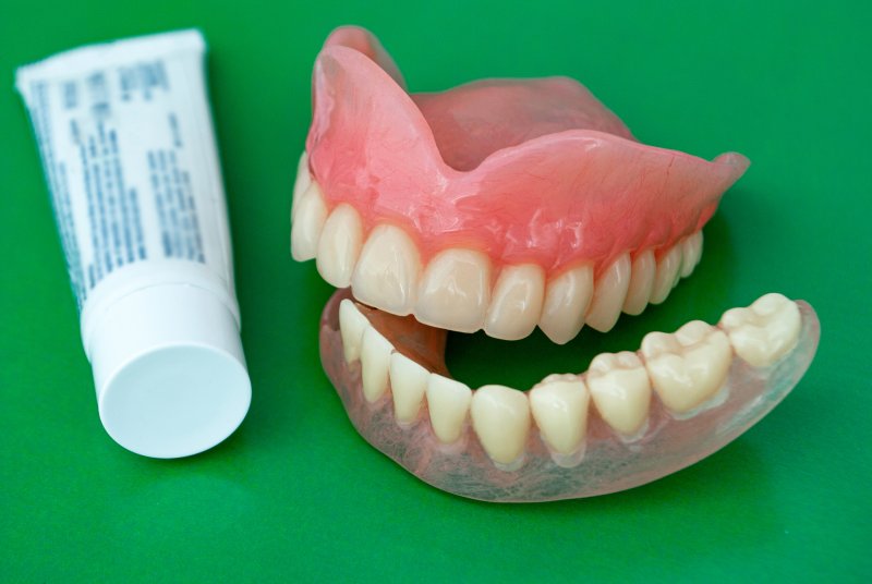 A tube of adhesive paste next to a pair of dentures